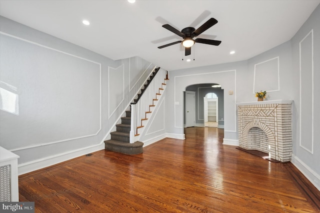 unfurnished living room featuring dark hardwood / wood-style flooring, a fireplace, and ceiling fan