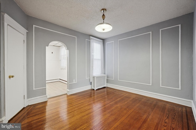 spare room with hardwood / wood-style flooring, radiator heating unit, a textured ceiling, and baseboard heating