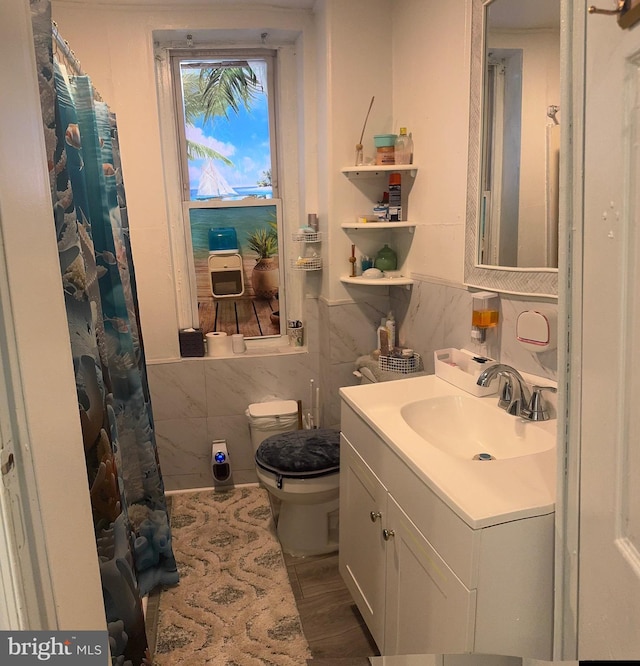 bathroom with hardwood / wood-style flooring, vanity, toilet, and tile walls