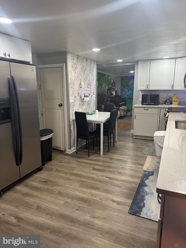 kitchen featuring white cabinetry, backsplash, hardwood / wood-style flooring, and stainless steel refrigerator with ice dispenser