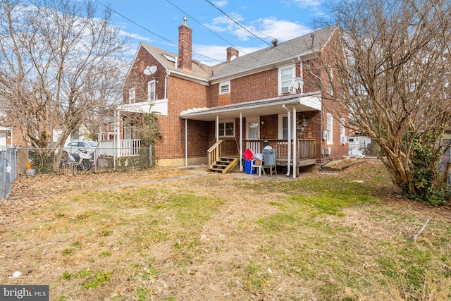 back of property featuring a lawn and covered porch