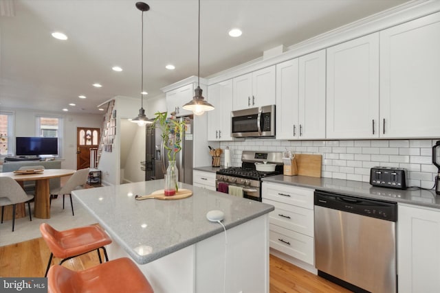 kitchen featuring decorative light fixtures, a center island, white cabinets, and appliances with stainless steel finishes