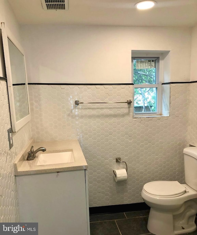 bathroom featuring tile walls, vanity, tile patterned flooring, and toilet