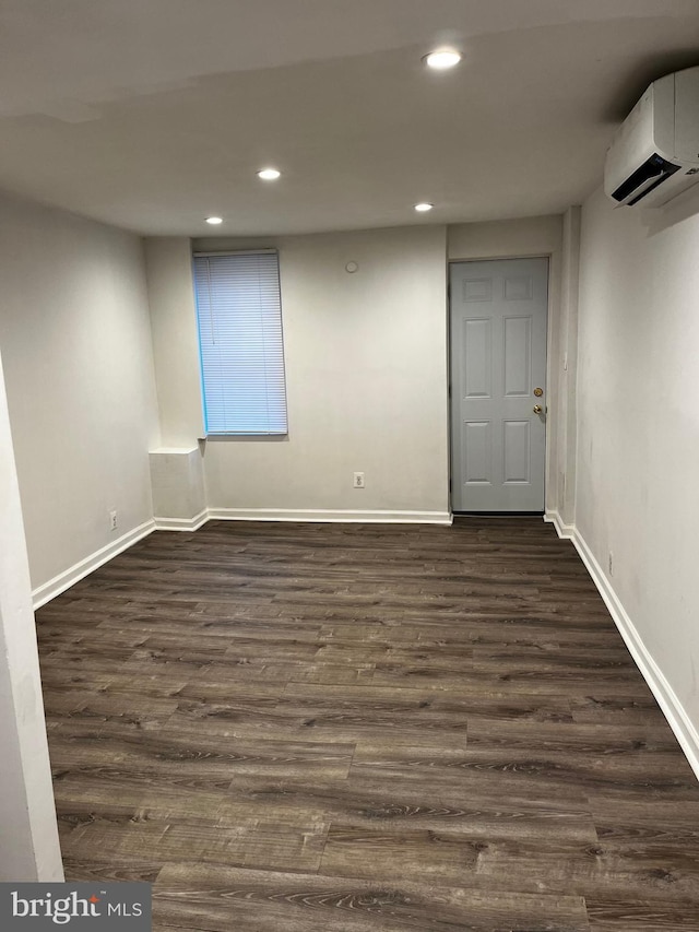 basement featuring an AC wall unit and dark wood-type flooring