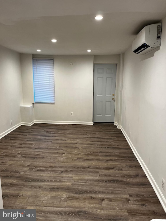 basement featuring a wall mounted air conditioner and dark wood-type flooring