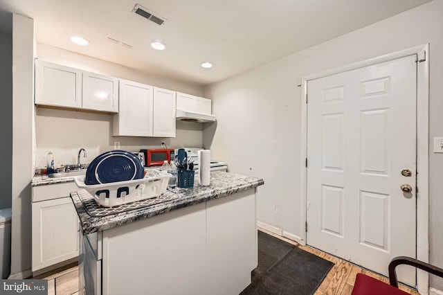 kitchen with white cabinetry, sink, hardwood / wood-style flooring, and a center island