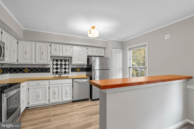 kitchen with sink, appliances with stainless steel finishes, ornamental molding, light hardwood / wood-style floors, and white cabinets