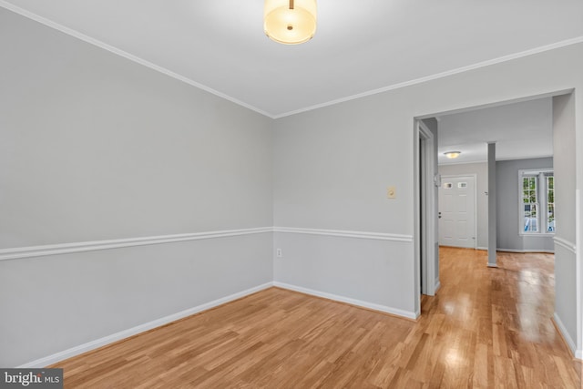 empty room with crown molding and light wood-type flooring