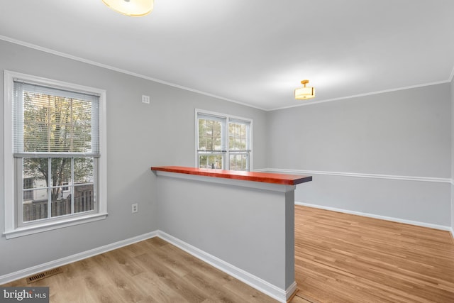 kitchen with crown molding, hardwood / wood-style flooring, a breakfast bar area, and kitchen peninsula