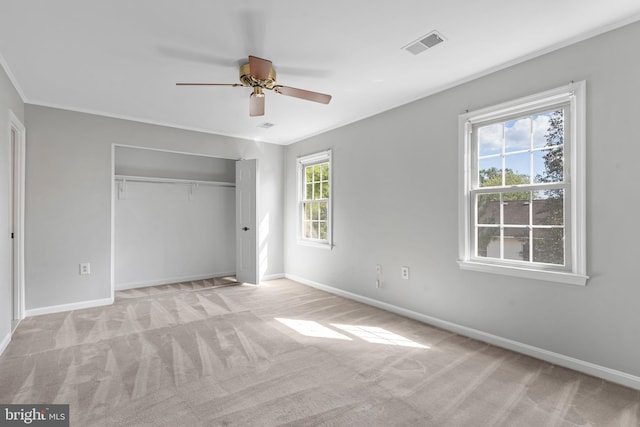 unfurnished bedroom featuring crown molding, a closet, ceiling fan, and light carpet