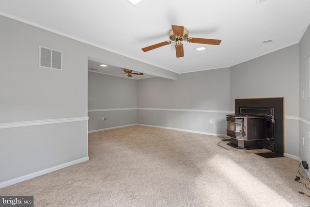 unfurnished living room featuring carpet floors, ceiling fan, and a wood stove