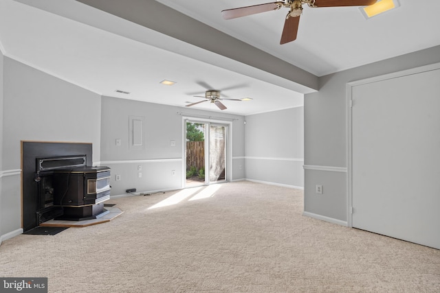 unfurnished living room with ceiling fan, light colored carpet, and a wood stove