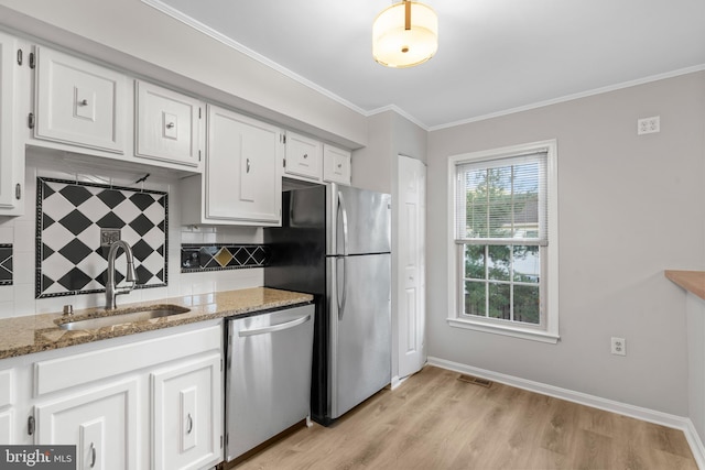 kitchen with light stone counters, white cabinetry, stainless steel appliances, and sink