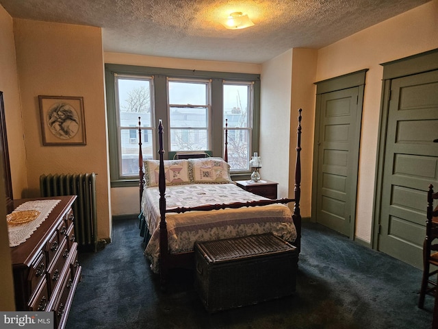 bedroom with radiator heating unit, a textured ceiling, and dark colored carpet