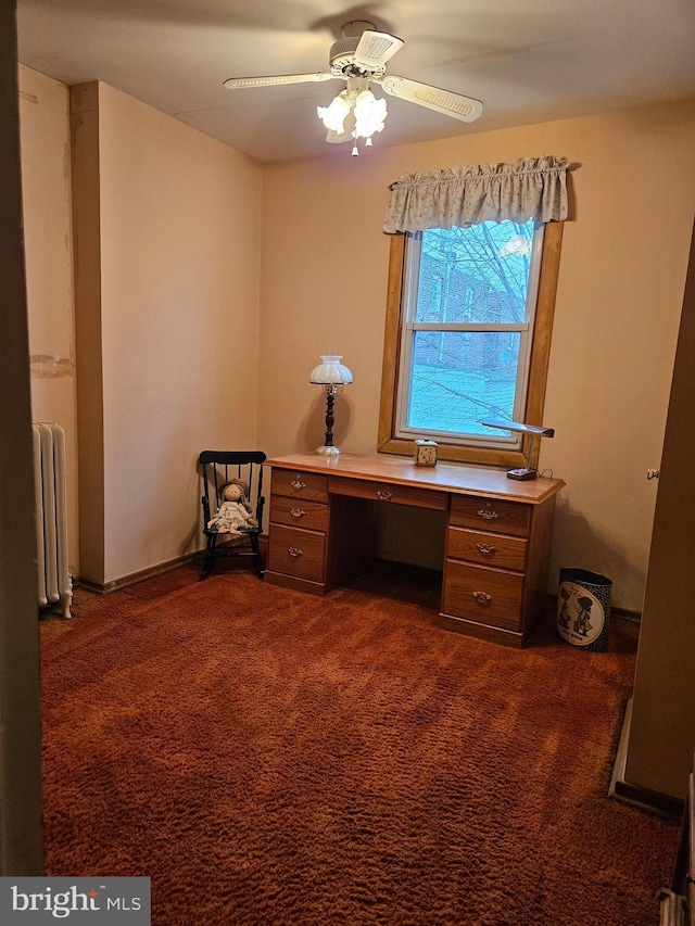 unfurnished office with radiator heating unit, ceiling fan, and dark colored carpet