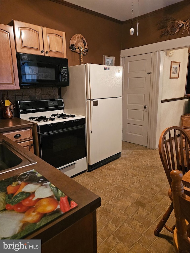 kitchen with white fridge, crown molding, range with gas cooktop, and backsplash