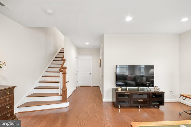 living area with stairs, wood finished floors, visible vents, and recessed lighting