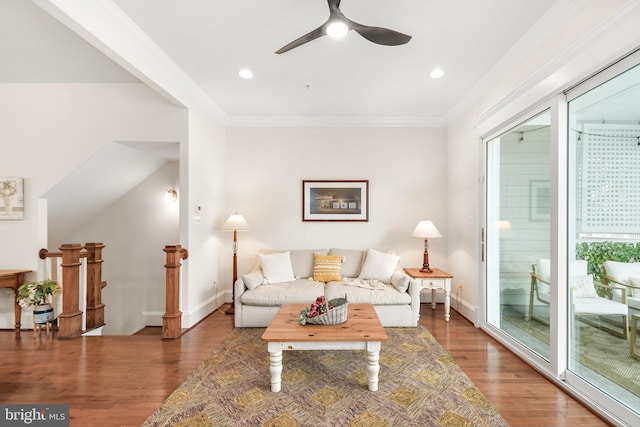 living area with baseboards, ceiling fan, wood finished floors, and crown molding