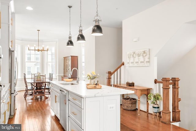 kitchen featuring white cabinets, wood-type flooring, appliances with stainless steel finishes, a kitchen island with sink, and a sink