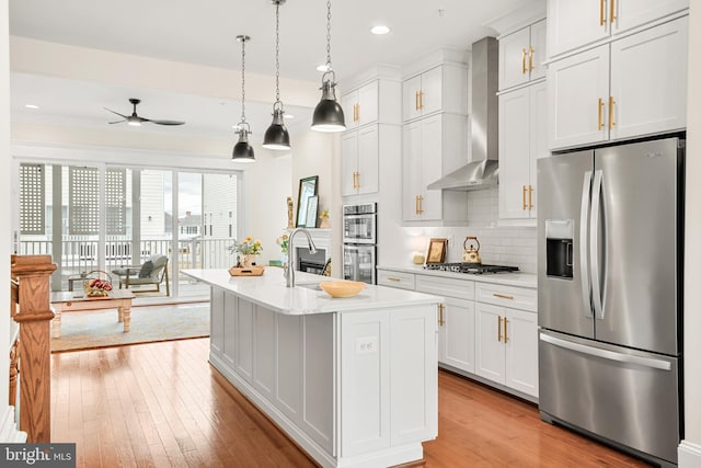 kitchen featuring a sink, light countertops, appliances with stainless steel finishes, backsplash, and wall chimney exhaust hood