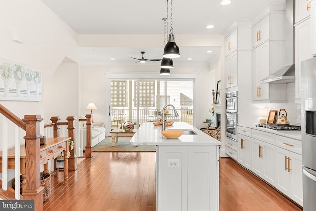 kitchen featuring a sink, stainless steel appliances, light countertops, light wood-style floors, and backsplash