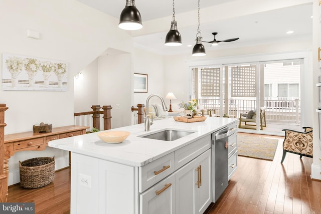 kitchen featuring dishwasher, a center island with sink, a sink, and wood finished floors