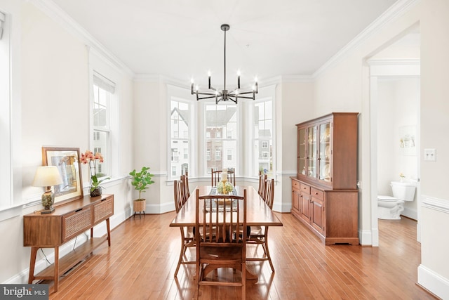 dining room featuring light wood-style floors, a chandelier, crown molding, and baseboards