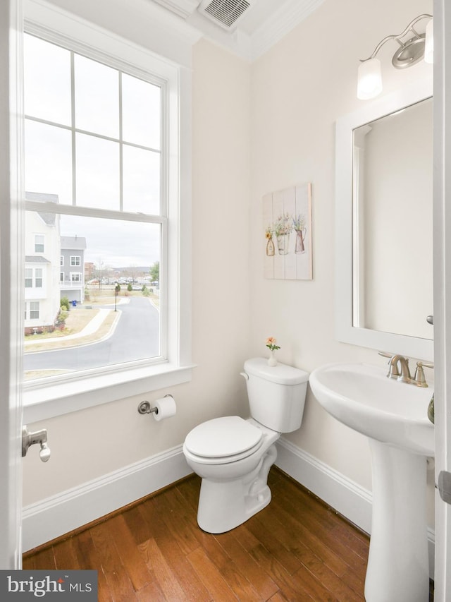 bathroom with baseboards, visible vents, toilet, and wood finished floors