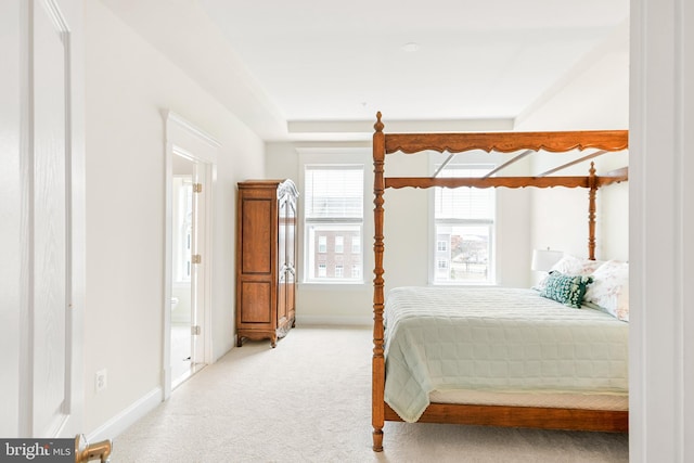 carpeted bedroom with connected bathroom and baseboards