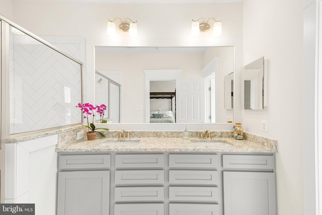 ensuite bathroom with double vanity, a sink, a shower with door, and connected bathroom