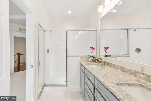 bathroom with double vanity, a stall shower, a sink, and visible vents