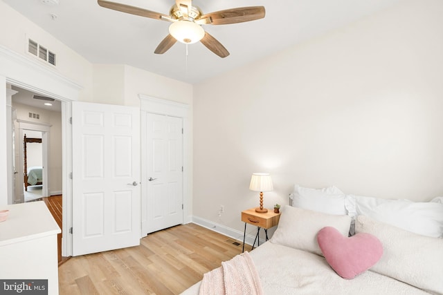 bedroom with ceiling fan, light wood-type flooring, visible vents, and baseboards