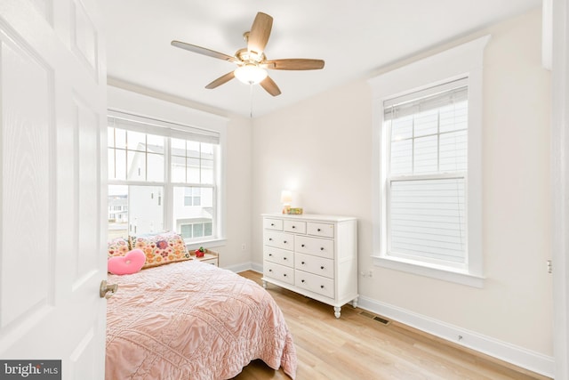 bedroom with light wood finished floors, a ceiling fan, visible vents, and baseboards