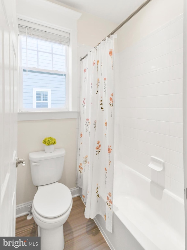 bathroom featuring toilet, shower / bath combination with curtain, baseboards, and wood finished floors