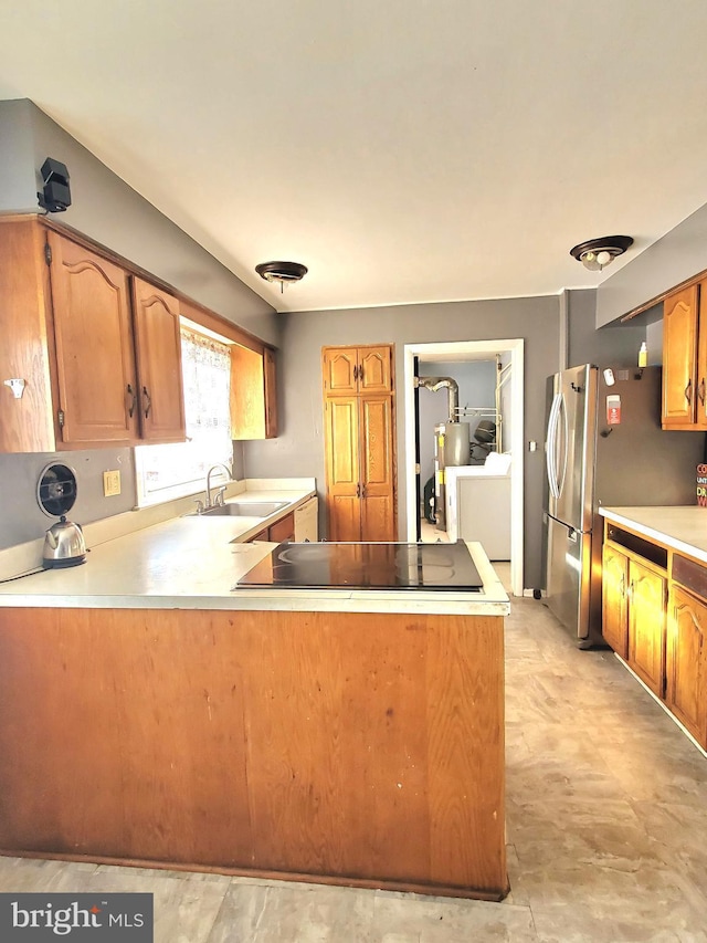 kitchen featuring sink, black electric stovetop, stainless steel fridge, and kitchen peninsula