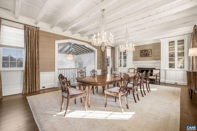 dining area featuring dark wood-type flooring, a chandelier, and beamed ceiling