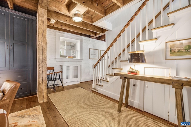 stairs with beam ceiling, wood ceiling, and wood-type flooring