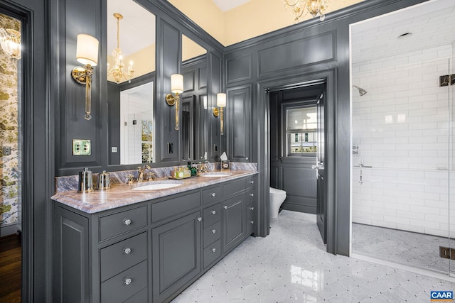 bathroom featuring vanity, toilet, a chandelier, and a tile shower