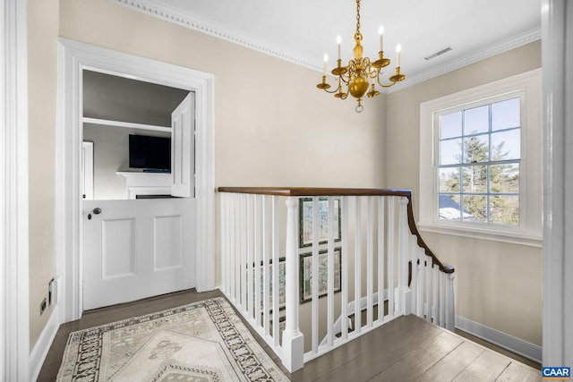 staircase with hardwood / wood-style flooring, ornamental molding, and a chandelier