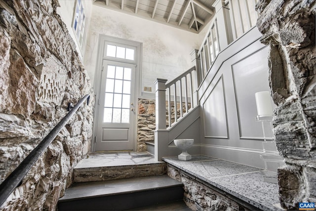 staircase featuring wood ceiling, a towering ceiling, and beam ceiling