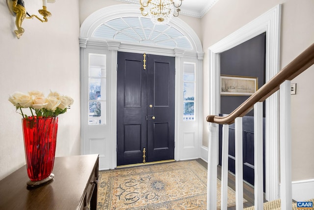 entrance foyer with crown molding and an inviting chandelier