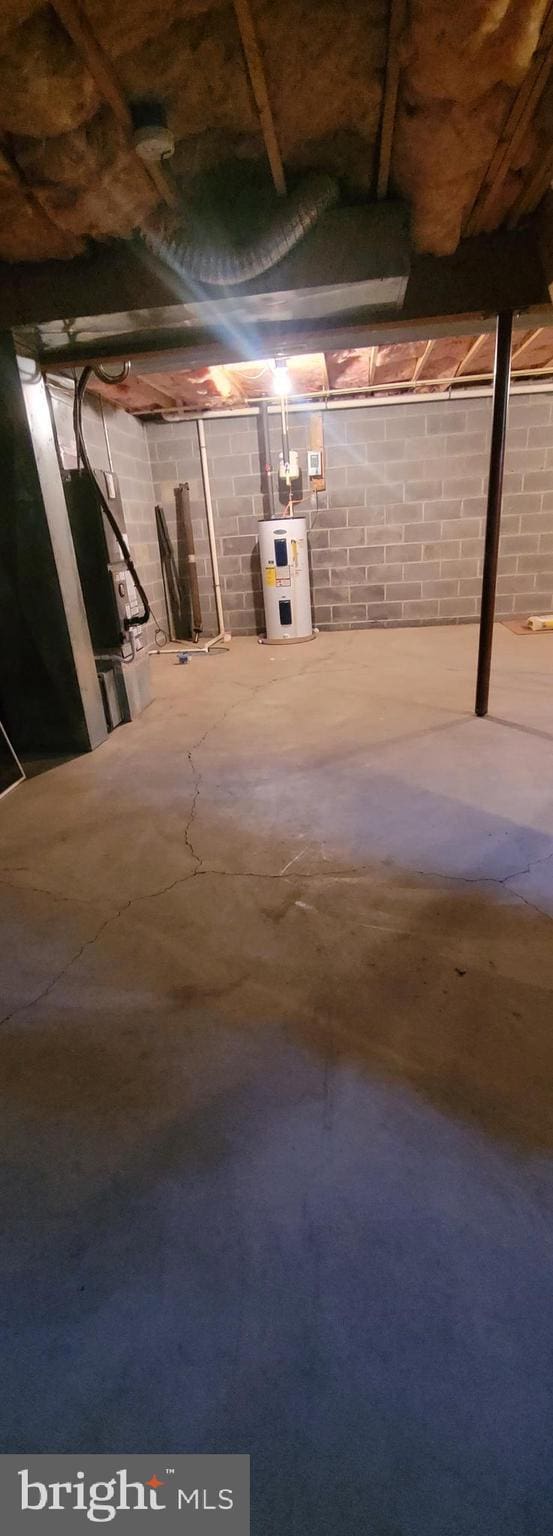 unfinished basement featuring concrete block wall and electric water heater