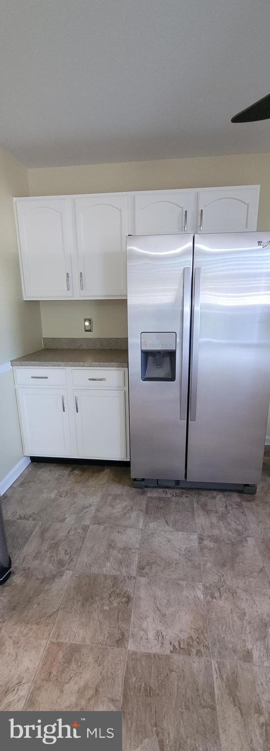 kitchen with stainless steel fridge and white cabinets