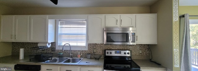 kitchen with stainless steel appliances, decorative backsplash, a sink, and white cabinets