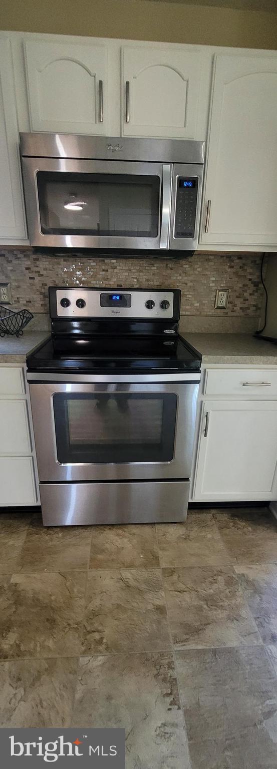 kitchen featuring appliances with stainless steel finishes, light countertops, white cabinetry, and decorative backsplash