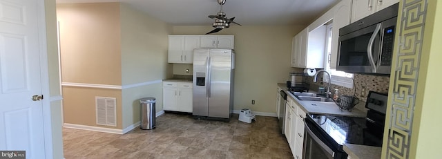 kitchen with stainless steel appliances, a sink, visible vents, white cabinets, and decorative backsplash