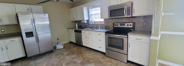 kitchen with decorative backsplash, appliances with stainless steel finishes, white cabinetry, a sink, and ceiling fan