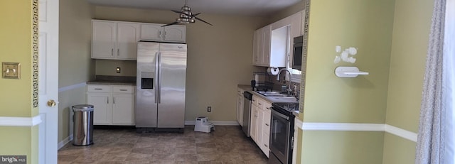 kitchen featuring baseboards, appliances with stainless steel finishes, white cabinets, and a sink