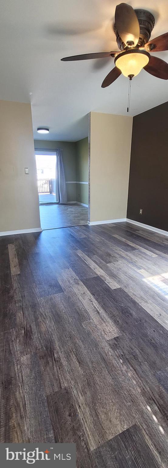 unfurnished living room with a ceiling fan, baseboards, and wood finished floors