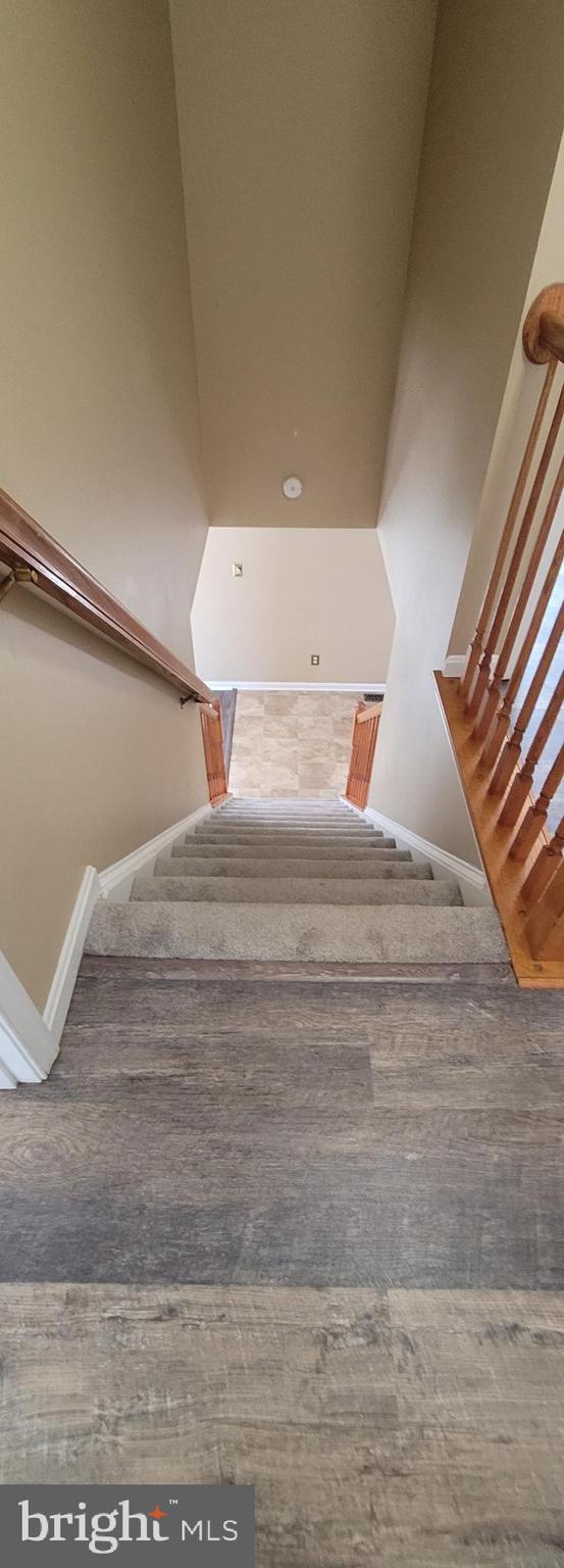 staircase featuring baseboards and wood finished floors